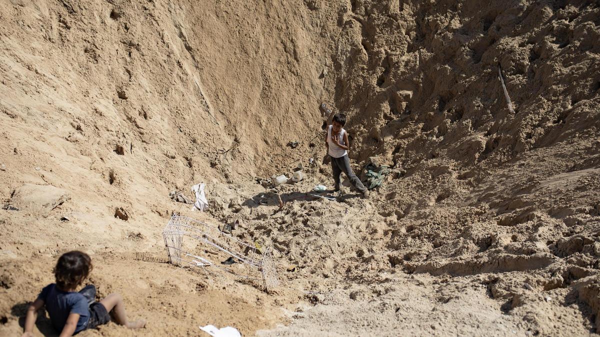 Unos niños palestinos inspeccionan la zona tras un ataque israelí en el campo para refugiados en Kahn Yunis