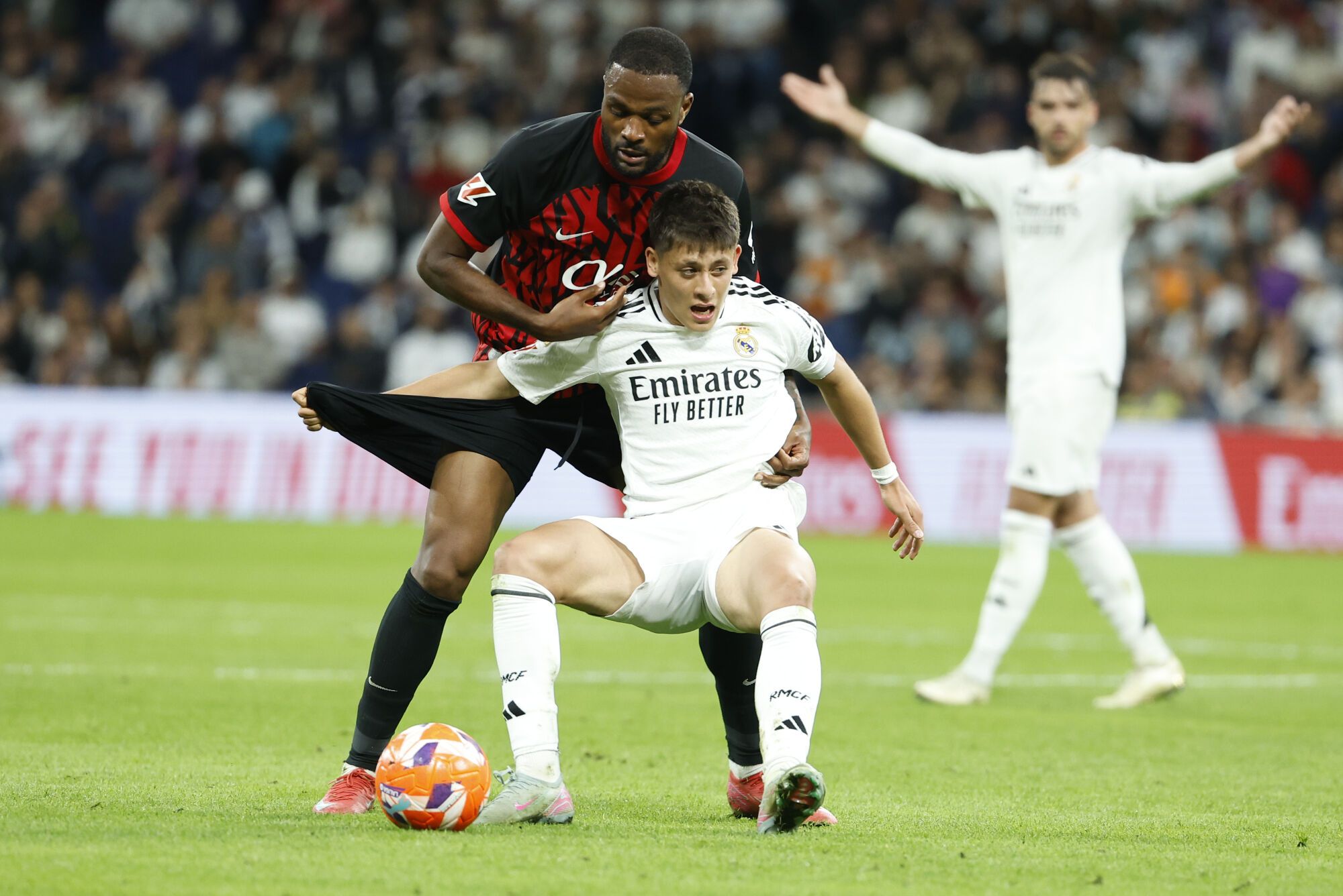 MADRID, 14/05/2025.- El centrocampista turco del Real Madrid Arda Guler (d) lucha con el canadiense Cyle Larin, del Mallorca, durante el partido de la jornada 36 de LaLiga de fútbol que Real Madrid y RCD Mallorca disputan este miércoles en el estadio Santiago Bernabéu. EFE/Chema Moya