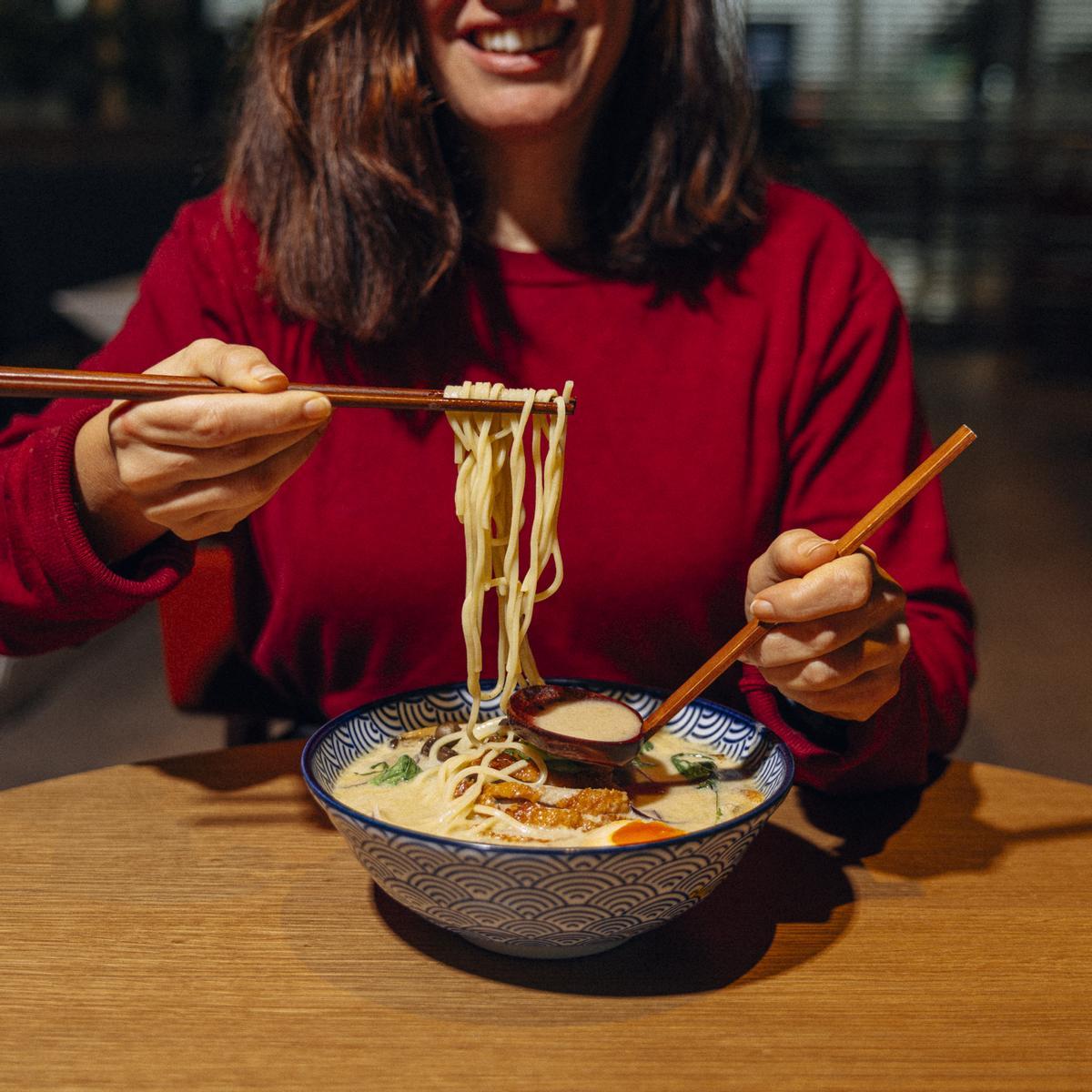 Una clienta come un plato de noodles en un establecimiento de la cadena Udon Asian Food.