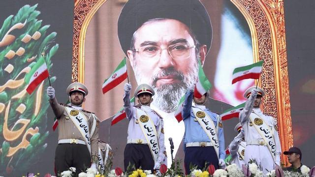 Membres de l’Exèrcit iranià onegen banderes davant d’un cartell de Mojtaba Khamenei. | ABEDIN TAHERKENAREHN / EFE