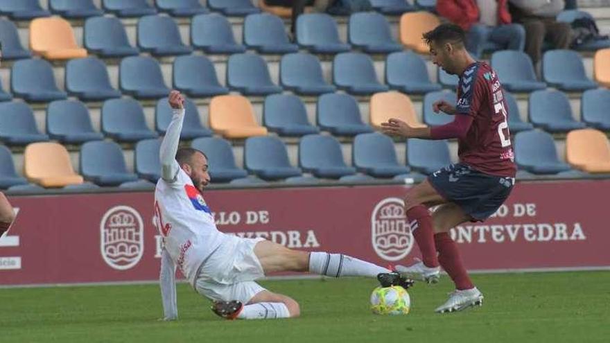 El jugador del Langreo Adrián Torre, tirándose al suelo para quitarle el balón a un rival del Pontevedra ayer en Pasarón.