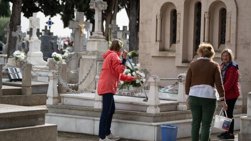 Tres mujeres limpian una sepultura en el cementerio de San Atilano.