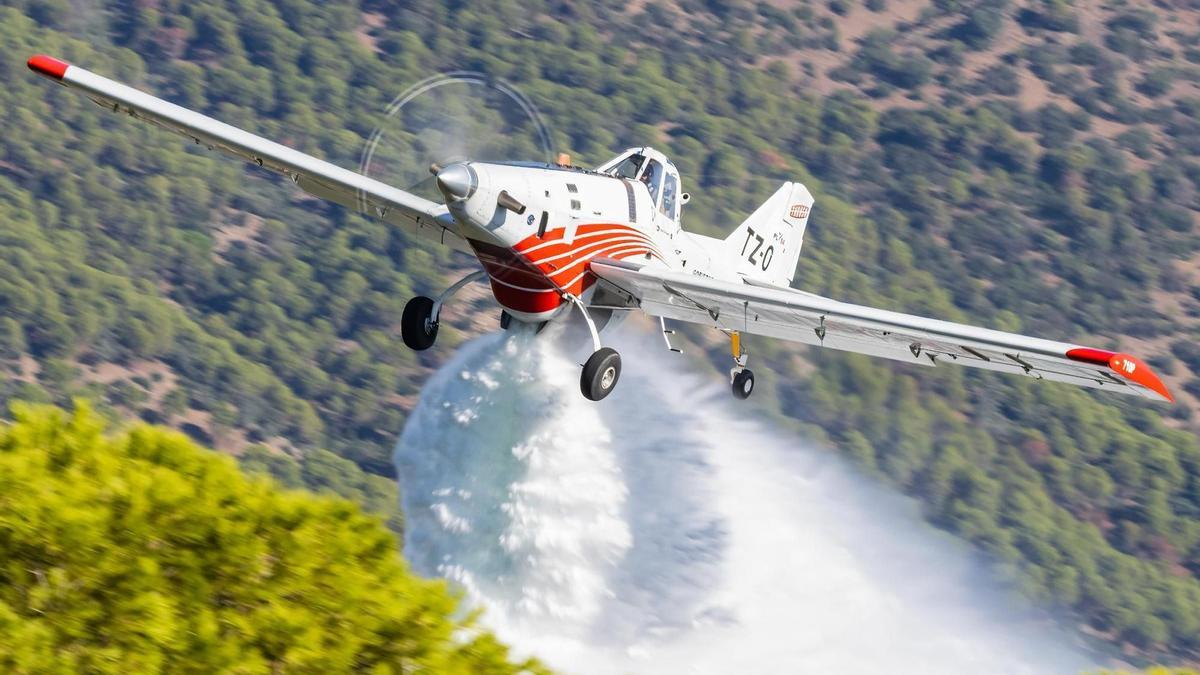 Una avioneta realizando una descarga de agua sobre una zona forestal.