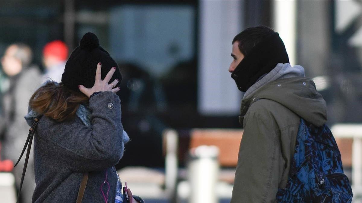 Una mujer y un hombre, protegidos del frío por gorro y bufanda, se cruzan en la Rambla del Poblenou de Barcelona, el 11 de enero del 2019.