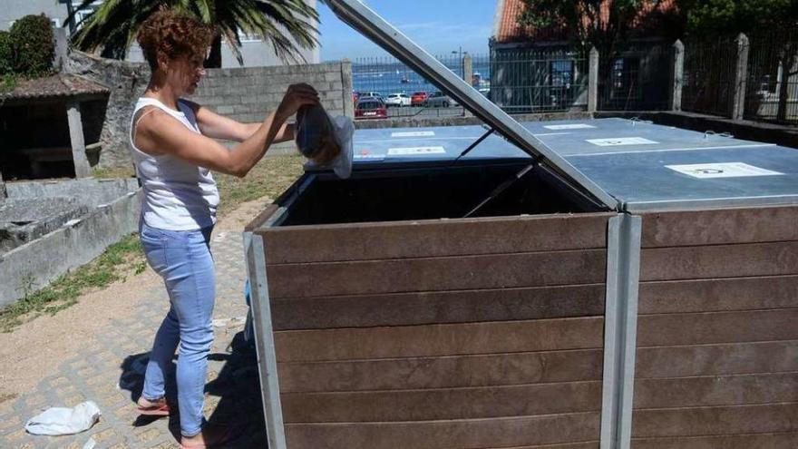 Una mujer arroja restos de comida en el compostero comunitario de O Naval. // Noé Parga