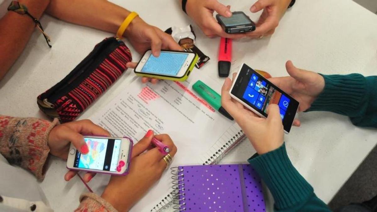 Varios alumnos usan su teléfono mientras estudian.