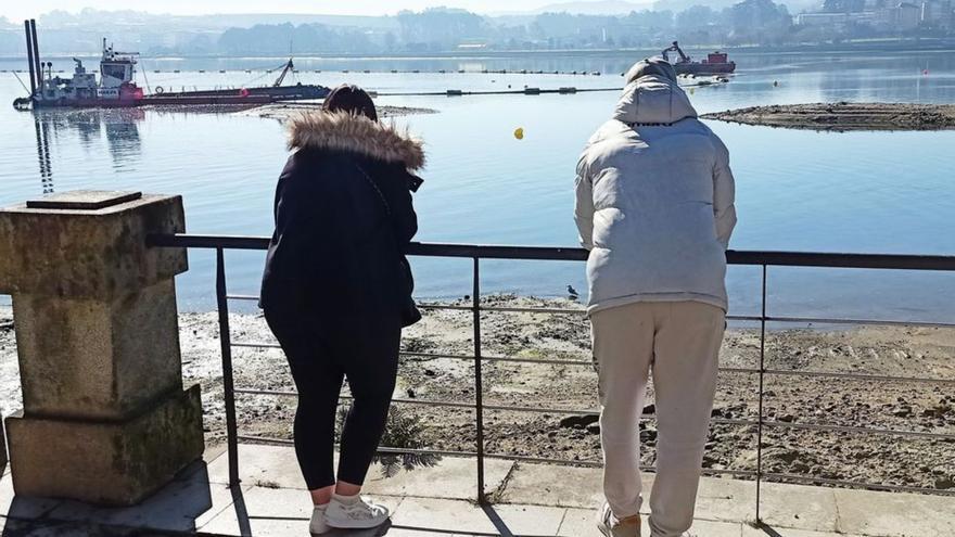 Vecinos contemplan desde el paseo cómo trabajan dos dragas.  |  // I.R.