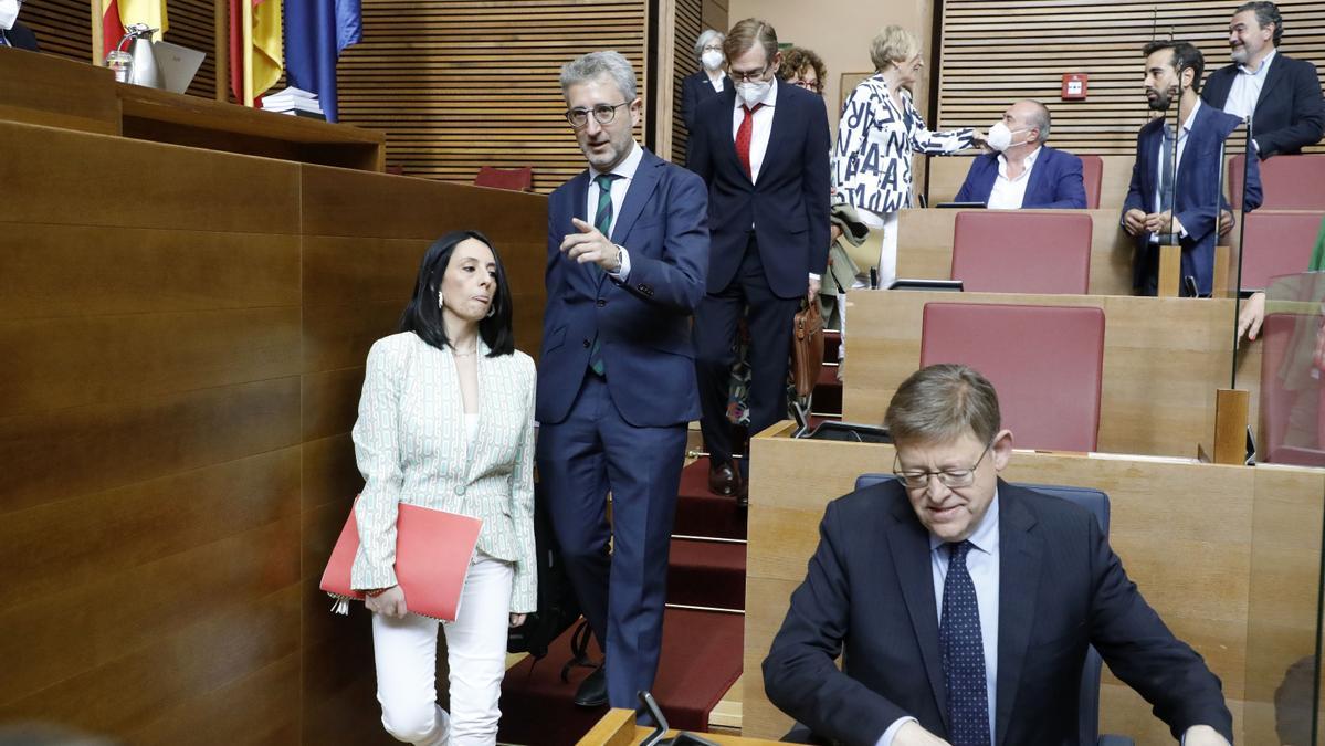 El conseller de Hacienda, Arcadi España, señala el escaño a la consellera de Política Territorial, Rebeca Torró