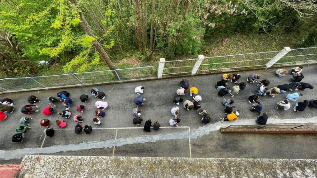 Alumnos y profesores del IES Valle de Turón dibujan con sus cuerpos el verso “Pido la paz y la palabra”. | LNE