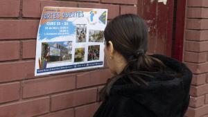 Una madre lee un cartel promocional de puertas abiertas, esta semana en un colegio de Barcelona.