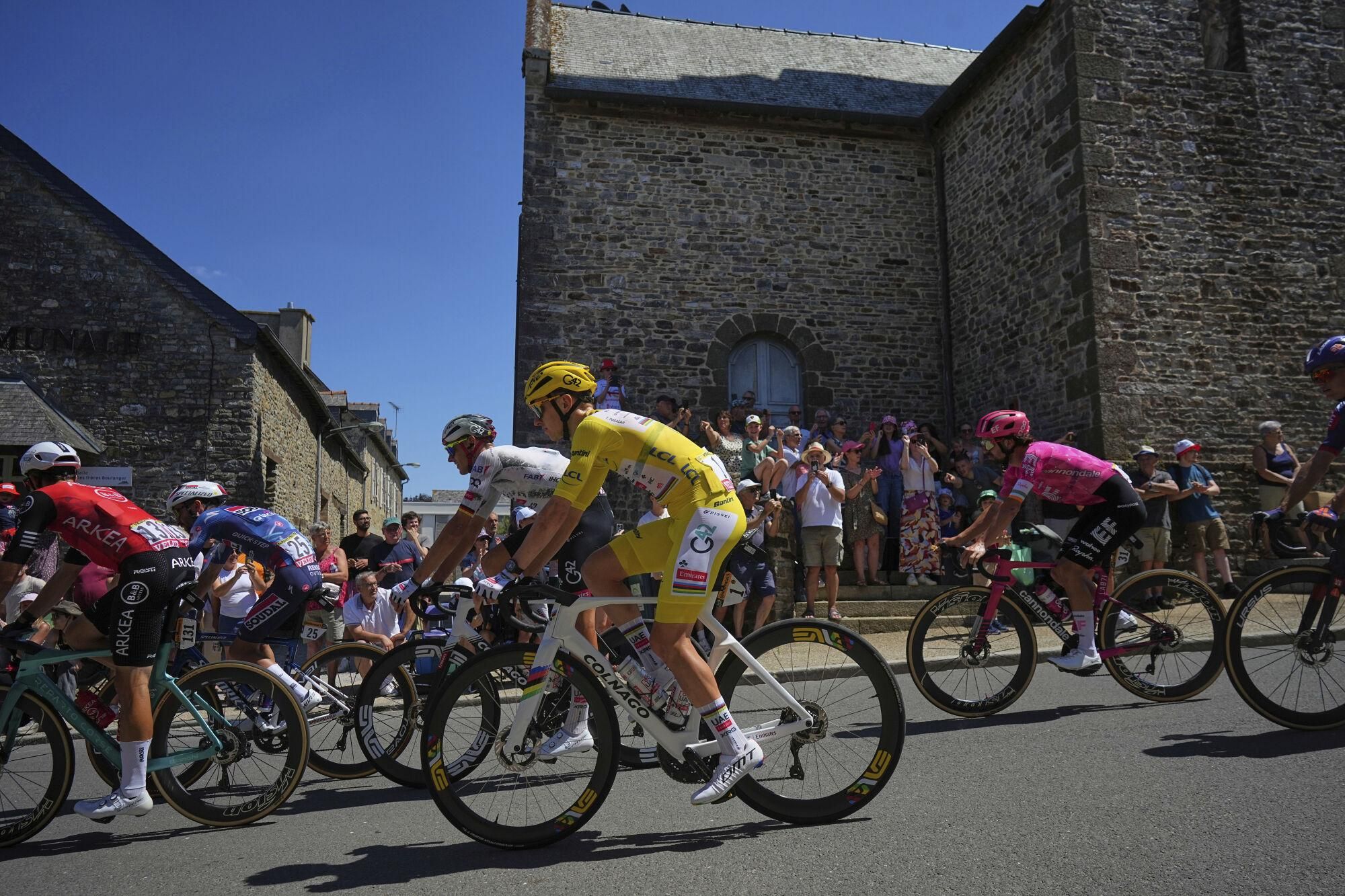 Ireland's Ben Healy, right in pink jersey, follows Slovenia's Tadej Pogacar, wearing the overall leader's yellow jersey, during the eighth stage of the Tour de France cycling race over 171.4 kilometers (106.5 miles) with start in Saint-Meen-le-Grand and finish in Laval Espace Mayenne, France, Saturday, July 12, 2025. (AP Photo/Thibault Camus)