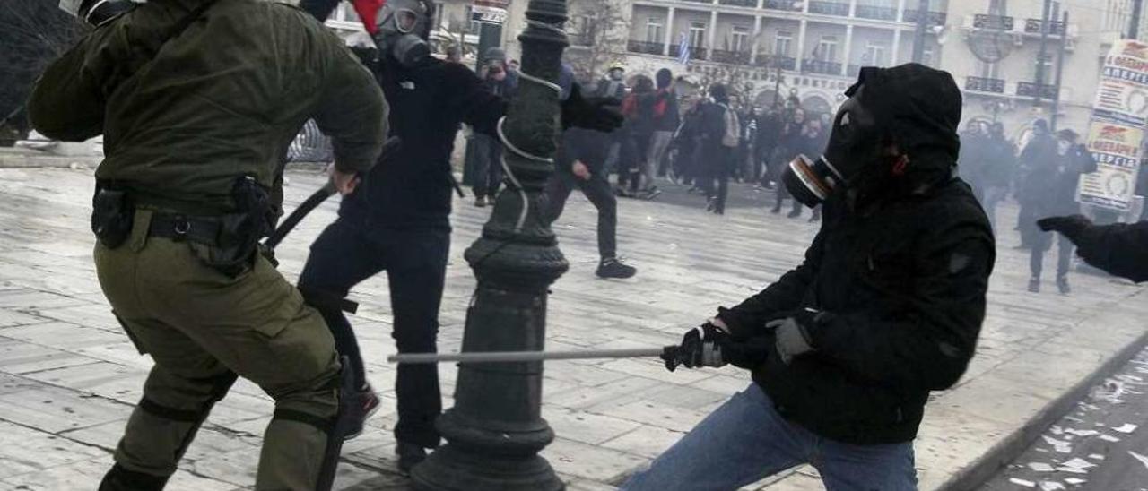 Manifestantes radicales se enfrentan a un policía antidisturbios tras la manifestación de Atenas. // Efe