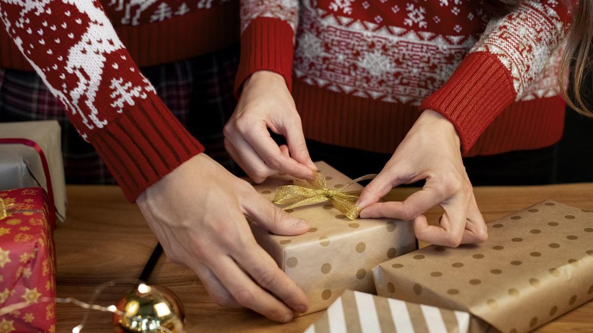 Dos personas envolviendo regalos en Navidad.