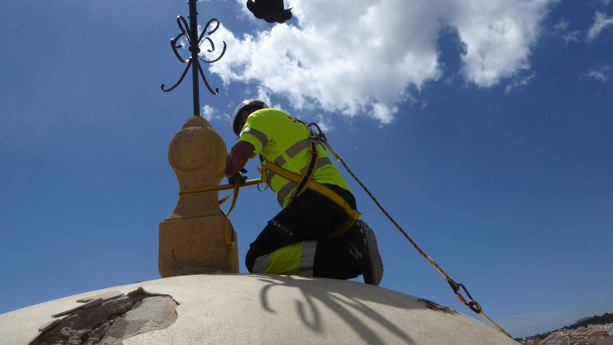 Un operario sujeta la veleta del campanario con cuerdas en una imagen donde también se aprecian otros desperfectos ocasionados por el rayo.