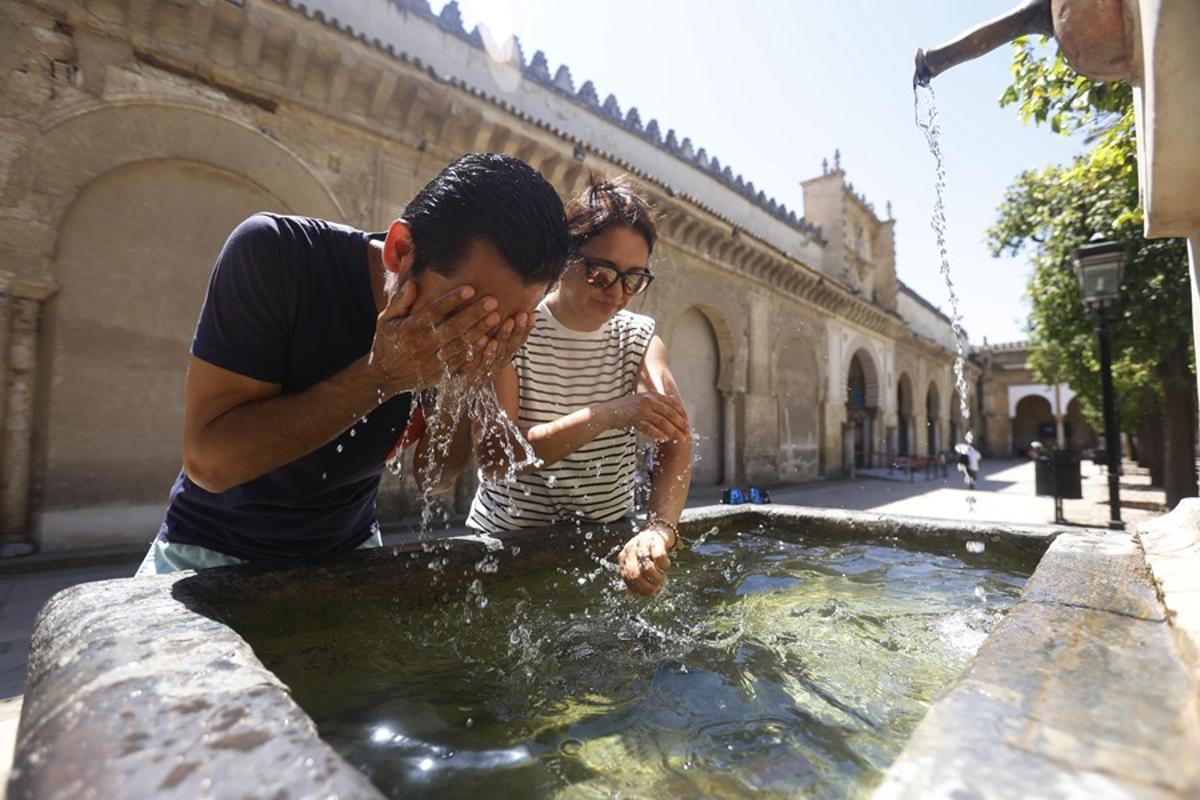 Unos turistas se refrescan en una fuente del Patio de los Naranjos de la Mezquita Catedral de Córdoba (España).