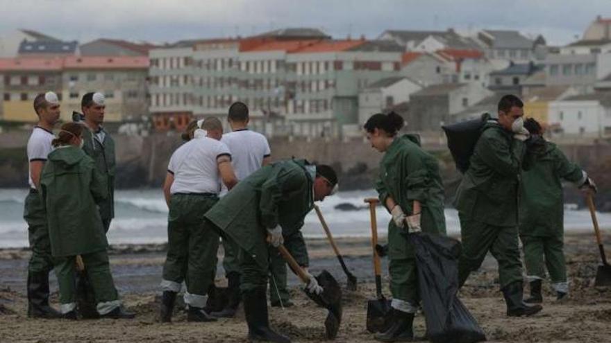 Militares de la Armada limpian restos de fuel en una playa de A Coruña. / carlos pardellas