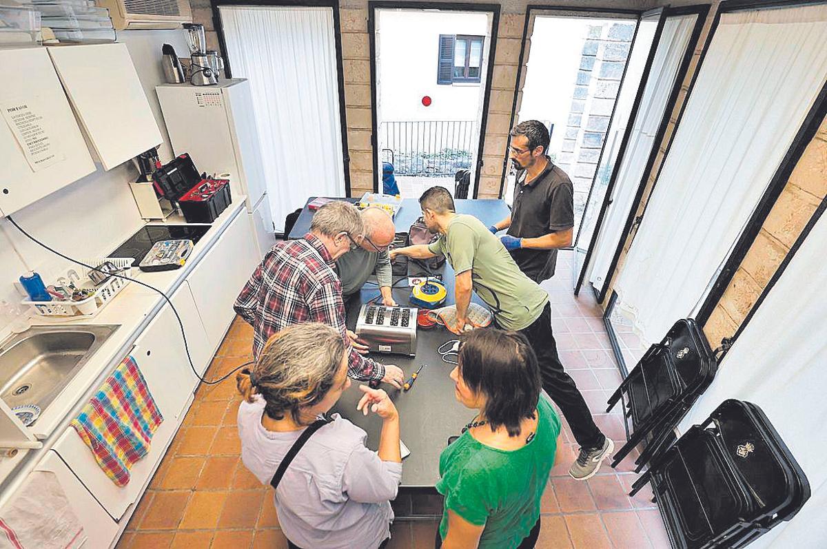 Varios voluntarios intentando reparar una manta eléctrica y una tostadora.
