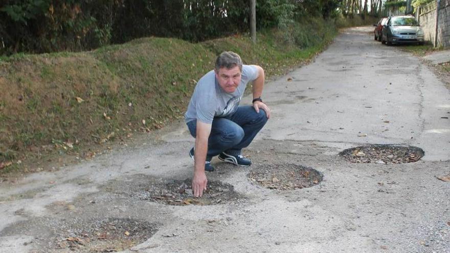 José Manuel González señala varios baches en la carretera de Pumarín.