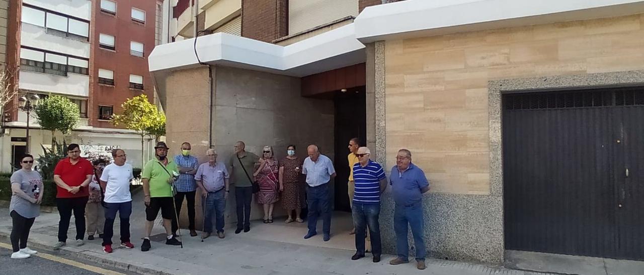 Arriba, los vecinos junto al edificio que alberga el «narcopiso». A la derecha, un grupo de residentes, junto a la manta con la que los traficantes presuntamente hacen señales a los clientes. | D. M.