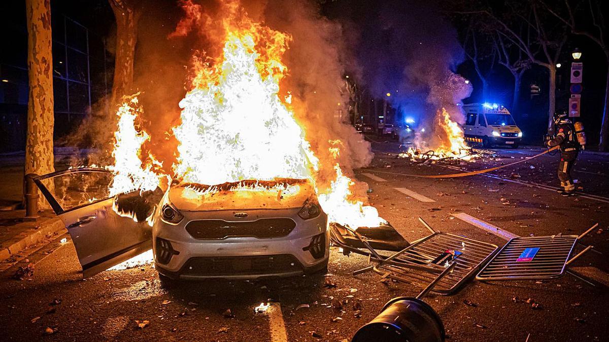 Un cotxe crema mentre un bomber intenta apagar un altre foc a Barcelona. | MANU MITRU