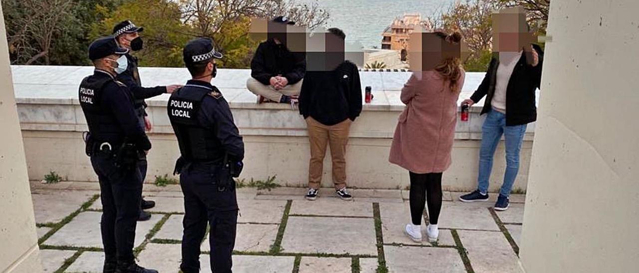 Policías locales identificando a unos jóvenes que consumían alcohol en la calle en Alicante. | INFORMACIÓN