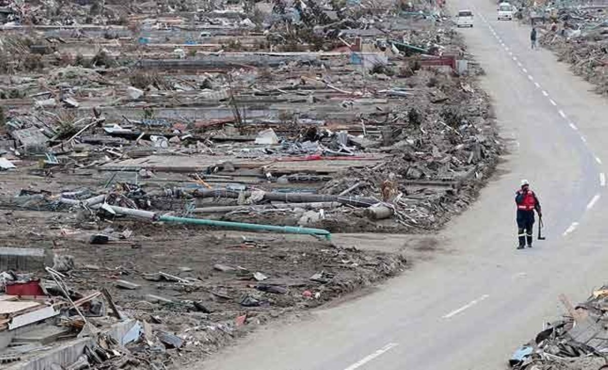 Un oficial de rescat sud-africà camina per la carretera durant una operació de recerca en un suburbi de Natori, a la prefectura de Miyagi (Japó).