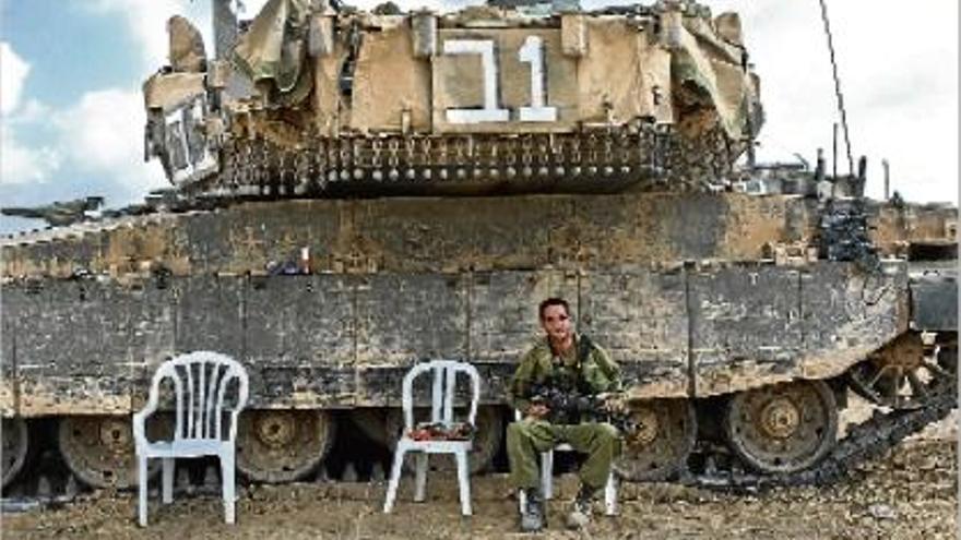 Un soldat israelià descansa davant d&#039;un tanc Merkava, al costat de la frontera amb la franja de Gaza