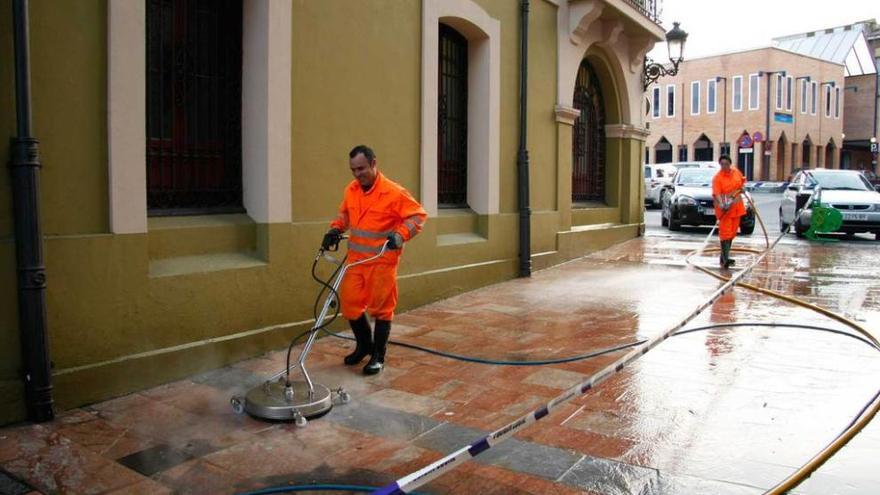 Dos operarios limpian las aceras en el entorno de la Casa Consistorial.