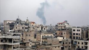 Una columna de humo se eleva sobre los escombros durante un bombardeo de las fuerzas gubernamentales sirias en Sarman, en Idlib.