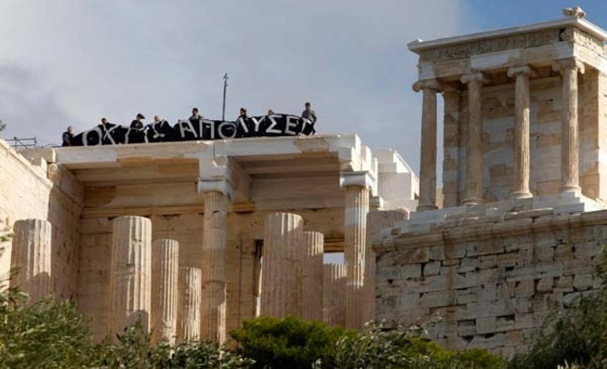 Trabajadores protestan contra los despidos en Grecia con una pancarta a la entrada de la Acrópolis.