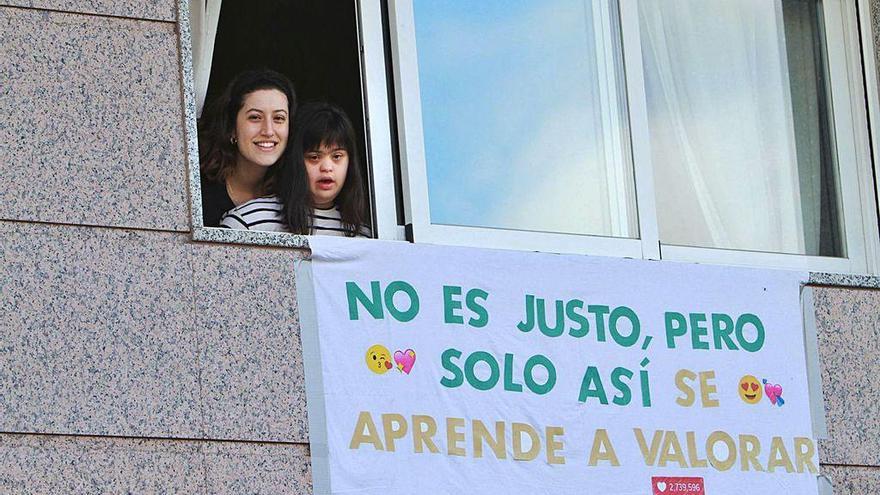 Dos hermanas se asoman a la ventana durante el confinamiento.