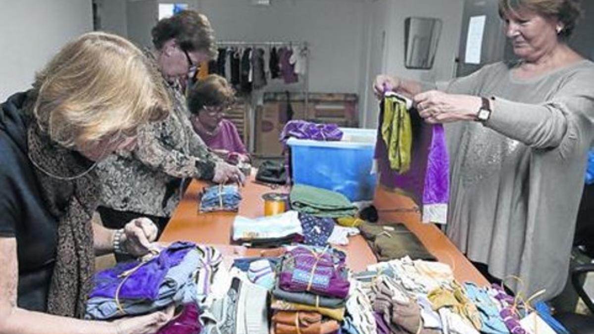 COLABORACIÓN. Cuatro voluntarias de la comunidad virtual Barcelona Actua preparan ropa infantil para entregar a las familias en el local de la calle de Planeta, en Gràcia.