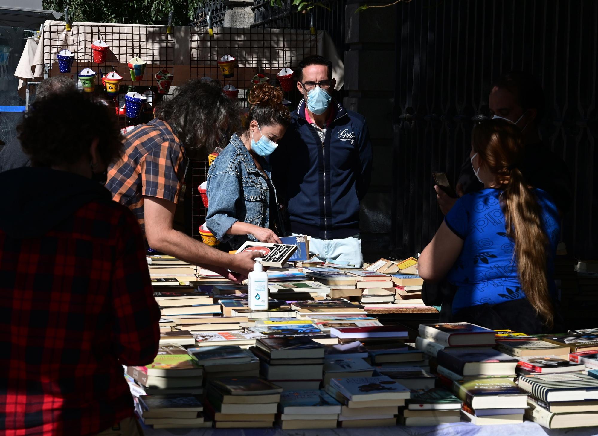 Varias personas ojean libros en uno de los puestos del Rastro de Madrid con mascarillas.