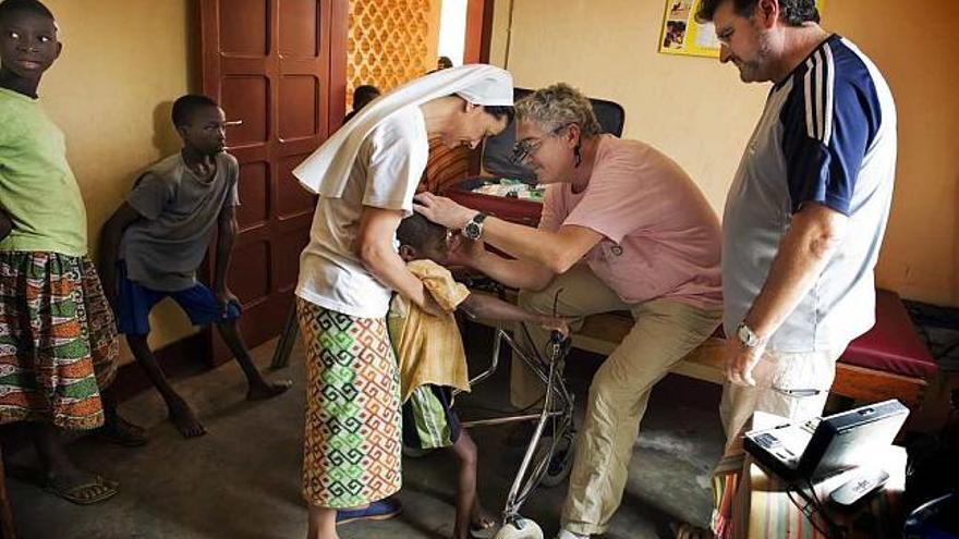 Dos voluntarios de la asociación examinan a un niño en el país africano.