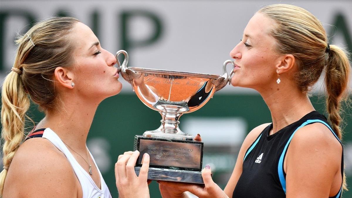 Kristina Mladenovic (derecha) y Timea Babos besan el trofeo de campeonas de dobles de Roland Garros.