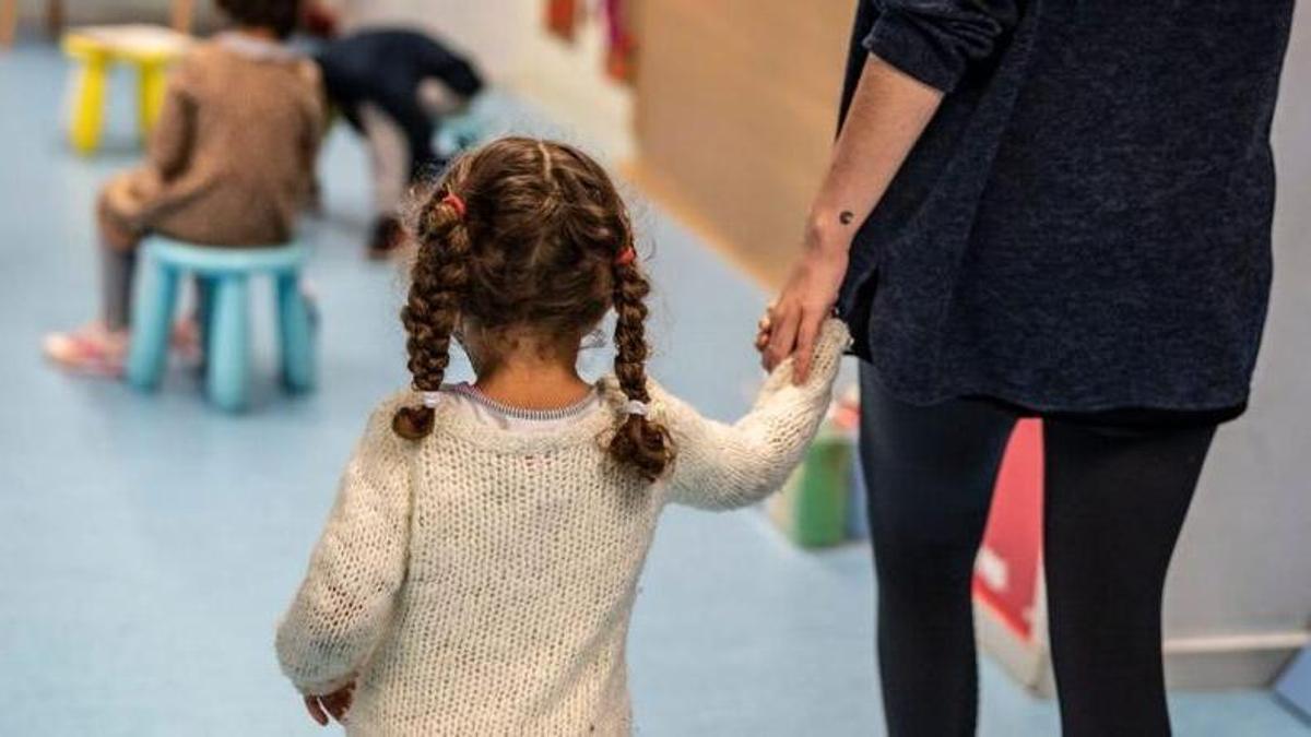 La monitora del espacio de canguro con una niña cogida de la mano.