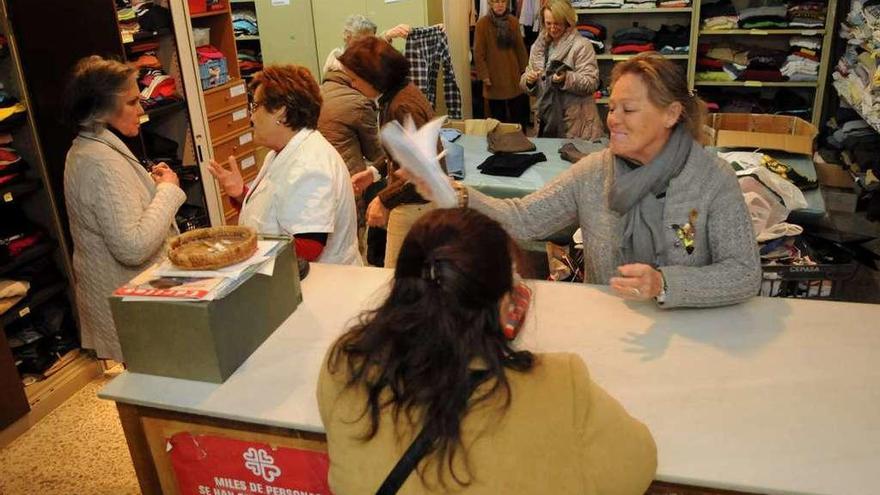 Voluntarios atienden a una mujer en uno de los roperos de Cáritas en Galicia.