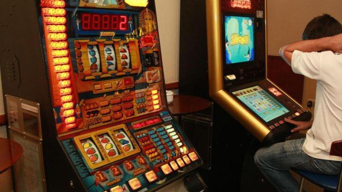 Persona jugando a una máquina tragaperras en un establecimiento de hostelería