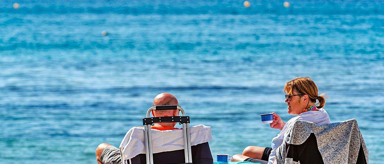 Un pareja de turistas disfrutando de sol en la playa de Levante de Benidorm.