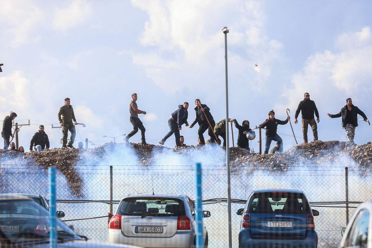 TOPSHOT - Farmers clash with riot police officers near Heraklion International Airport, as police block the main access road in Heraklion, on the island of Crete, on December 8, 2025. Farmers on Crete on Monday clashed with riot police near the Greek islands international airports in a burgeoning protest wave related to an EU subsidy probe. (Photo by Costas METAXAKIS / AFP)