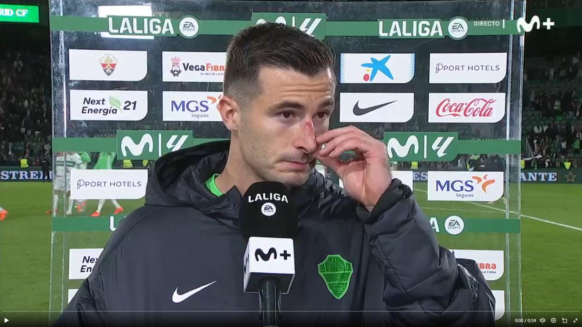 Iñaki Peña, con la nariz herida, atiende a la tele a pie de campo tras acabar el Elche-Real Madrid