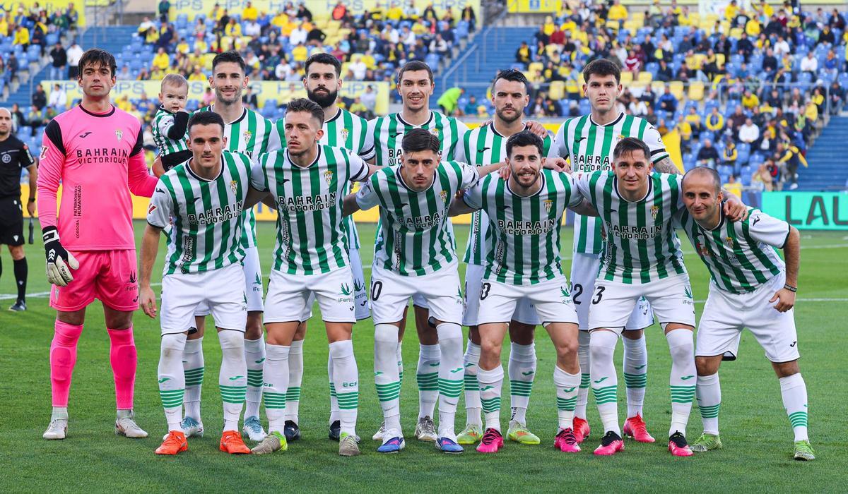 Once inicial del Córdoba CF en su visita a la UD Las Palmas, junto a un futbolista del equipo Genuine blanquiverde.