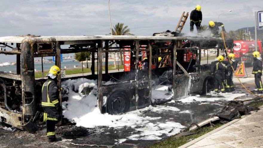 Los bomberos trabajan en la extinción del incendio del autobús de la EMT, en el Paseo Marítimo.