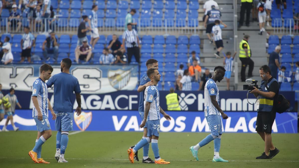 Los jugadores del Málaga CF se marchan cabizbajos tras el empate con el Huesca.