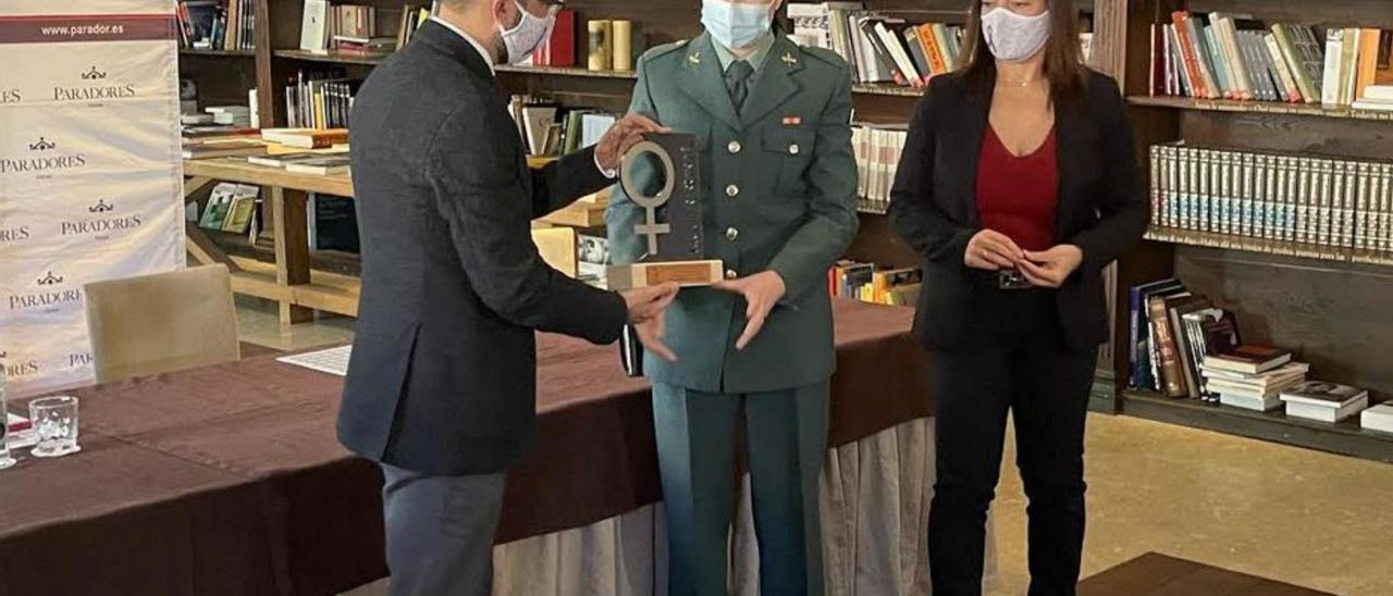 El alcalde, José Víctor Rodríguez, en la biblioteca del parador de Corias, entregando a la agente Elena Menéndez la distinción en presencia de la concejala de Mujer e Igualdad, Carmen López. | Rep. de T. C.