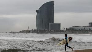 Un surfista se dispone a entrar en el agua de la playa de la Barceloneta, este 10 de noviembre.