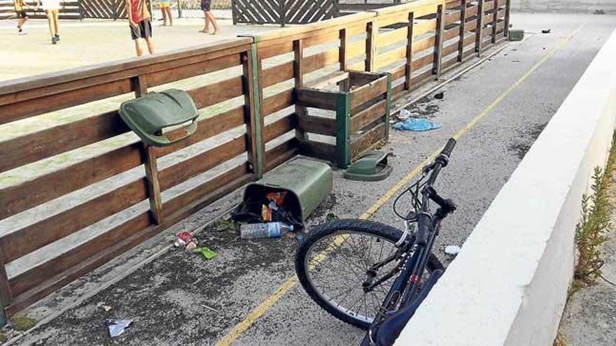 Una papelera rota junto a una zona deportiva para niños.