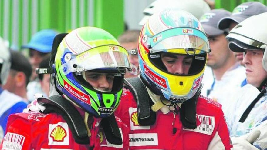 Fernando Alonso, a la derecha, conversa con su compañero Felipe Massa al término de la sesión de clasificación disputada ayer en Interlagos.