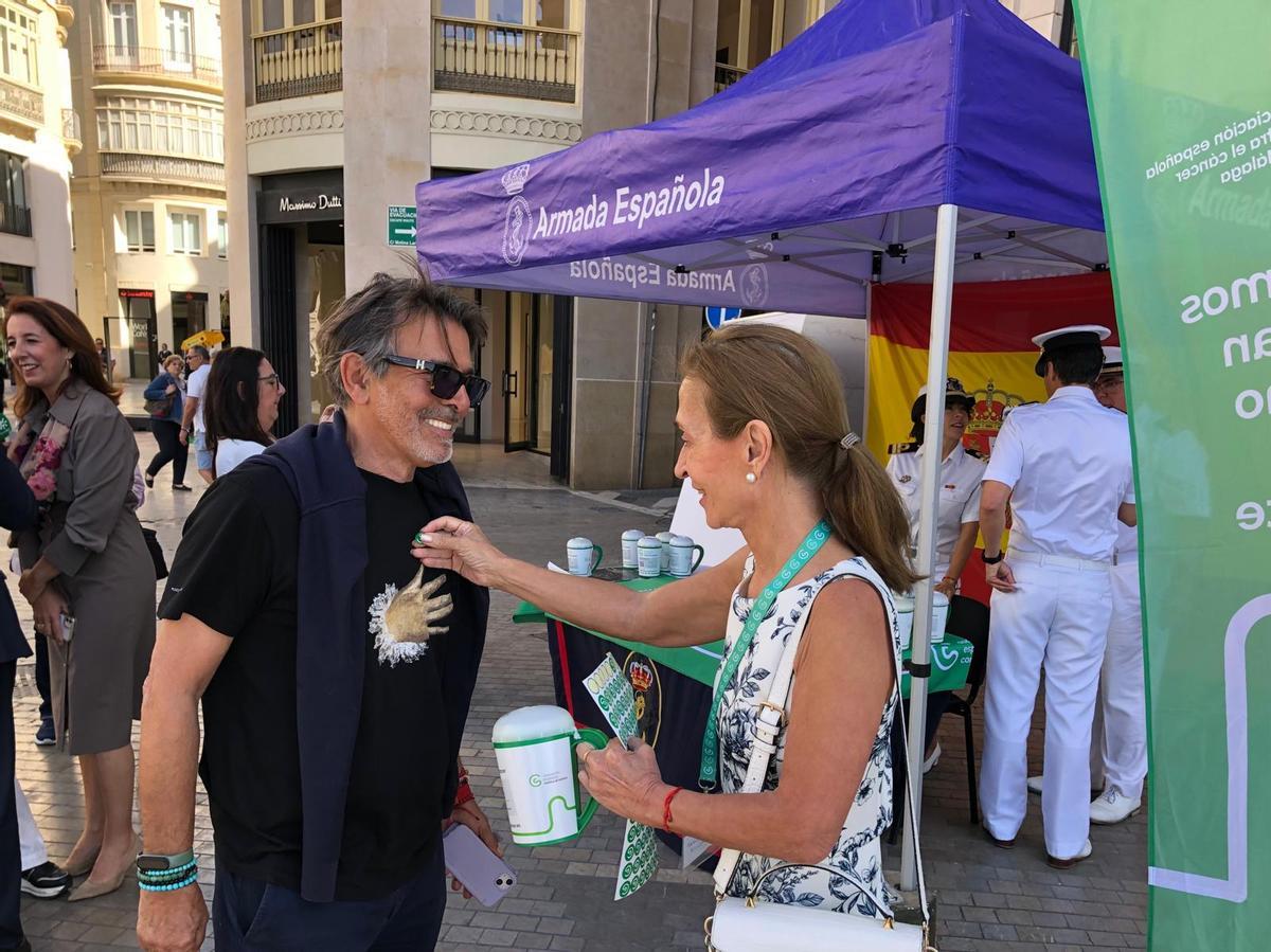 La voluntaria Mari Luz Aguilar coloca a un pegatina a un ciudadano tras realizar una donación