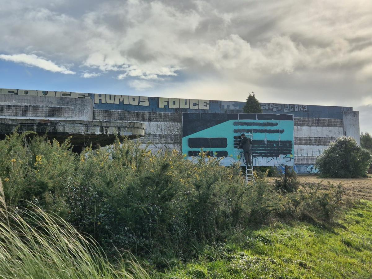 Un operario borra el cartel de venta de la antigua nave de Flex en la N-VI